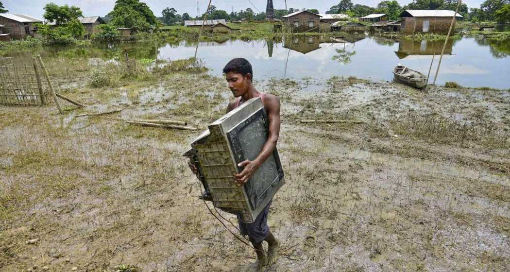 A villager moves his belongings to safety from a flood-affected area in Kaliabor, Nagaon district, Assam.