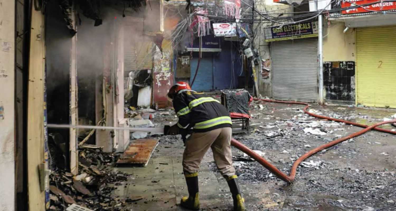 A firefighter tries to douse the fire a day after it broke out at the Marwari Katra market, in Chandni Chowk on Friday. 