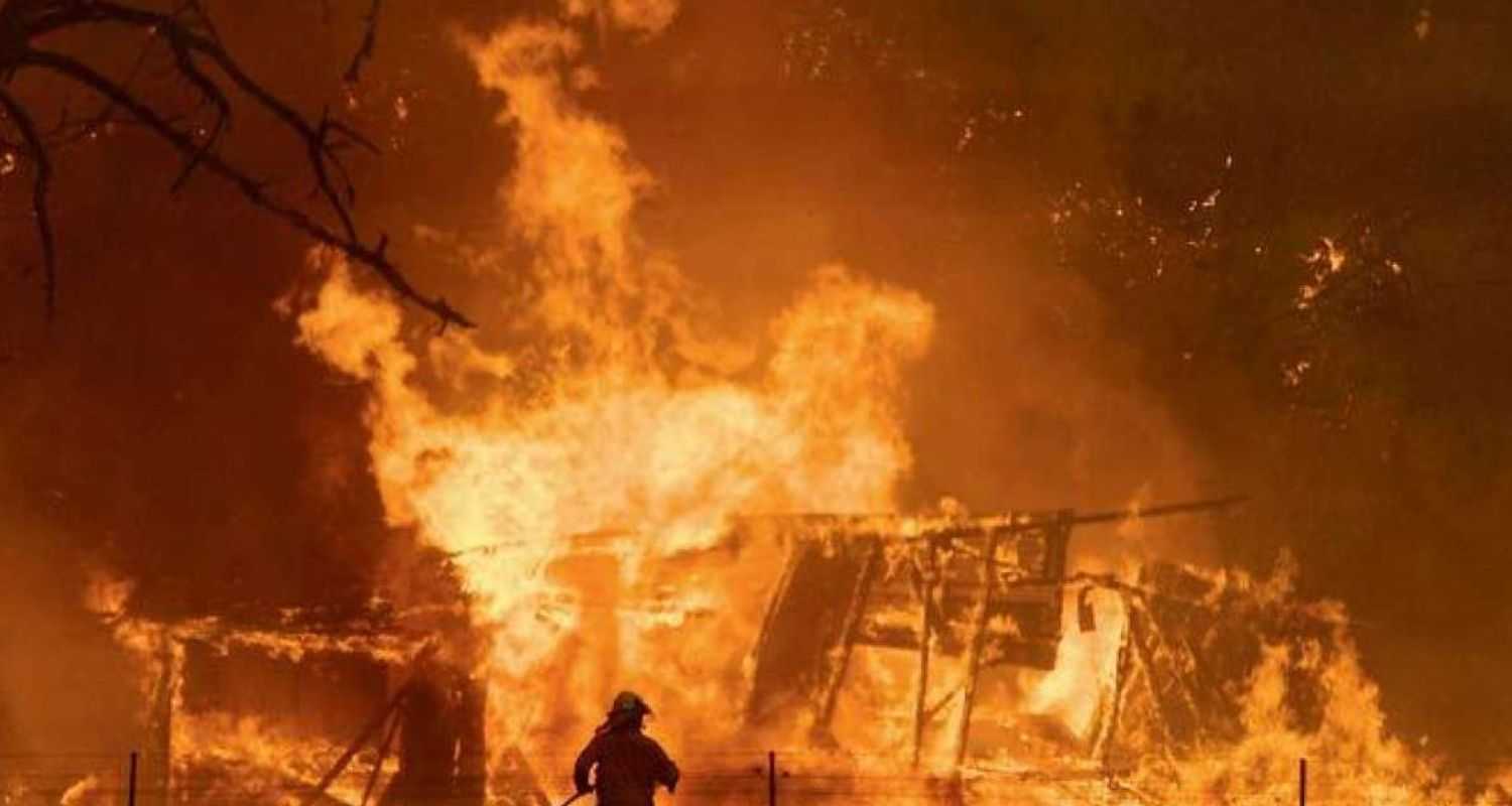 A man stands next to a huge flame in Santiago, Chile where wildfires have led to 123 dead and hundreds missing