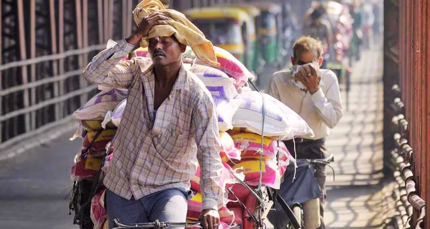 A man mops sweat from his brow while transporting goods on his cycle rickshaw across New Delhi's Old Yamuna bridge in sweltering weather.