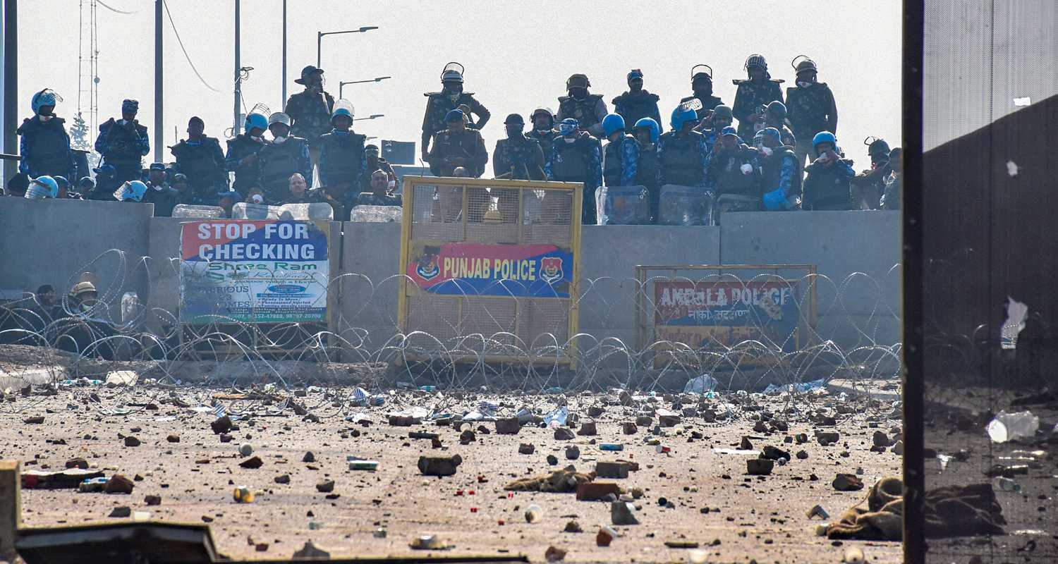 Security personnel stand guard as brick bats and stones lie on the roads at the Punjab-Haryana Shambhu border during farmers' 'Delhi Chalo' march, near Patiala district. 