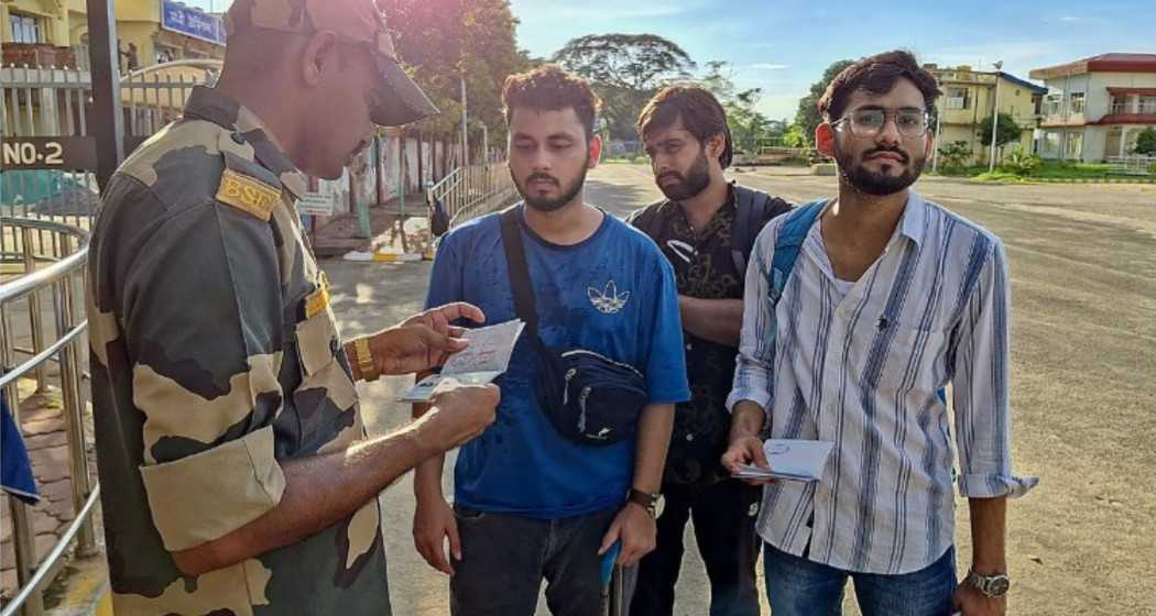 Students gather at the Indian border, their passports being scrutinised by a BSF personnel, following the outbreak of violence in Bangladesh.