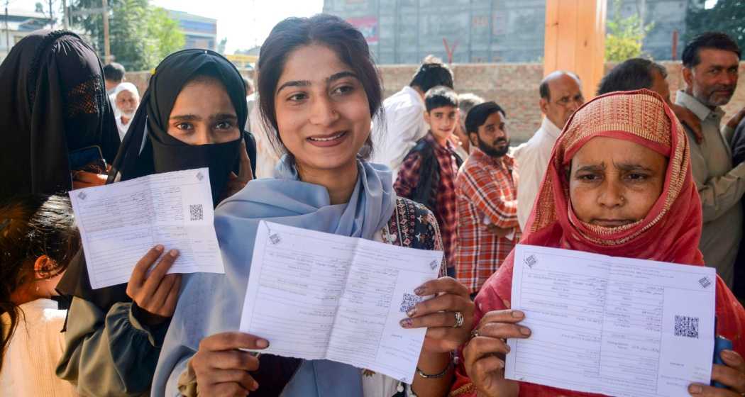 First time voters Rahila Younis (C), Humaira Jan (L) and others show their voting slips as they wait to cast votes at a polling station at Bijbehara during the first phase of Jammu and Kashmir Assembly elections, in Anantnag district, Wednesday, Sept. 18, 2024.