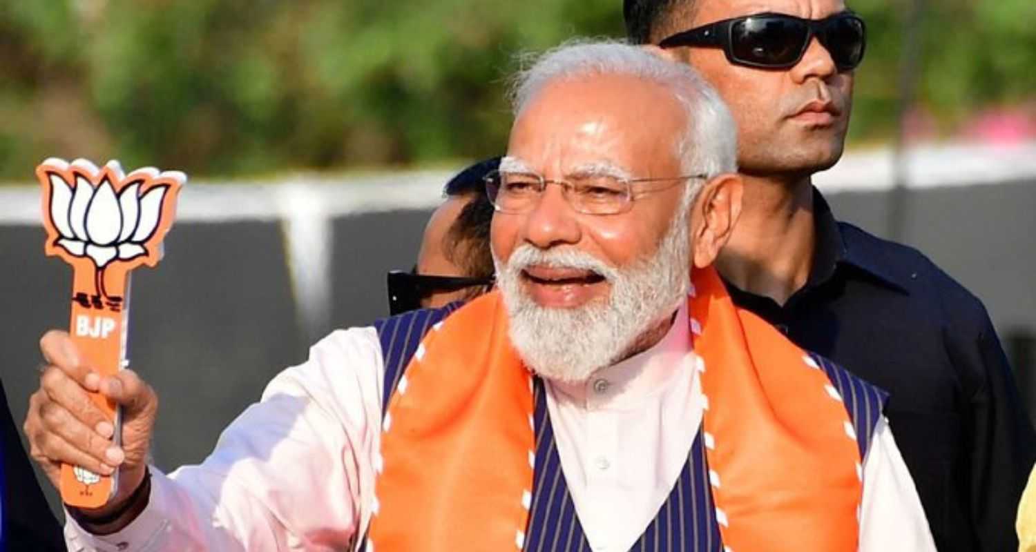 PM Modi shows the BJP insignia to supporters during an election campaign for the ongoing Lok Sabha Elections taking place across India.