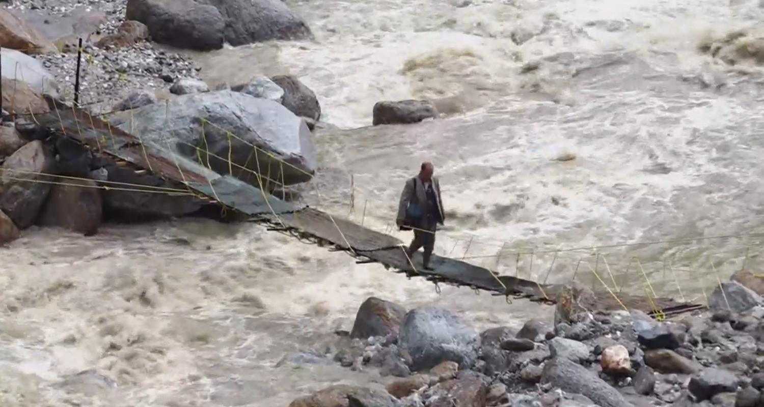 A man crosses a bridge at an affected site following cloudburst at Samej village, in the Rampur area of Shimla.