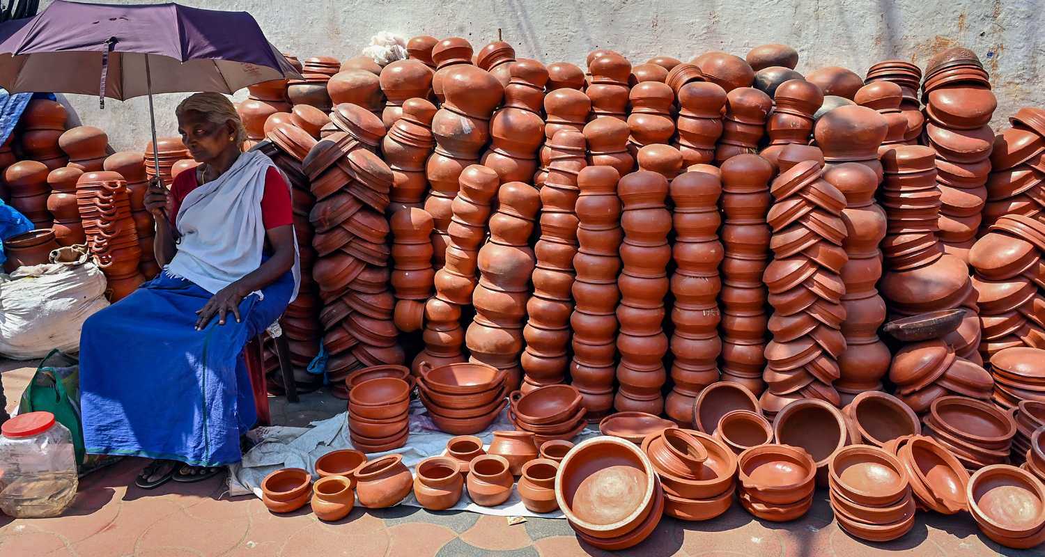 Clay pot vendor patiently awaits customers before Attukal Pongala, a 10-day religious festival at Attukal Bhagavathy Temple, Thiruvananthapuram, Kerala, India."