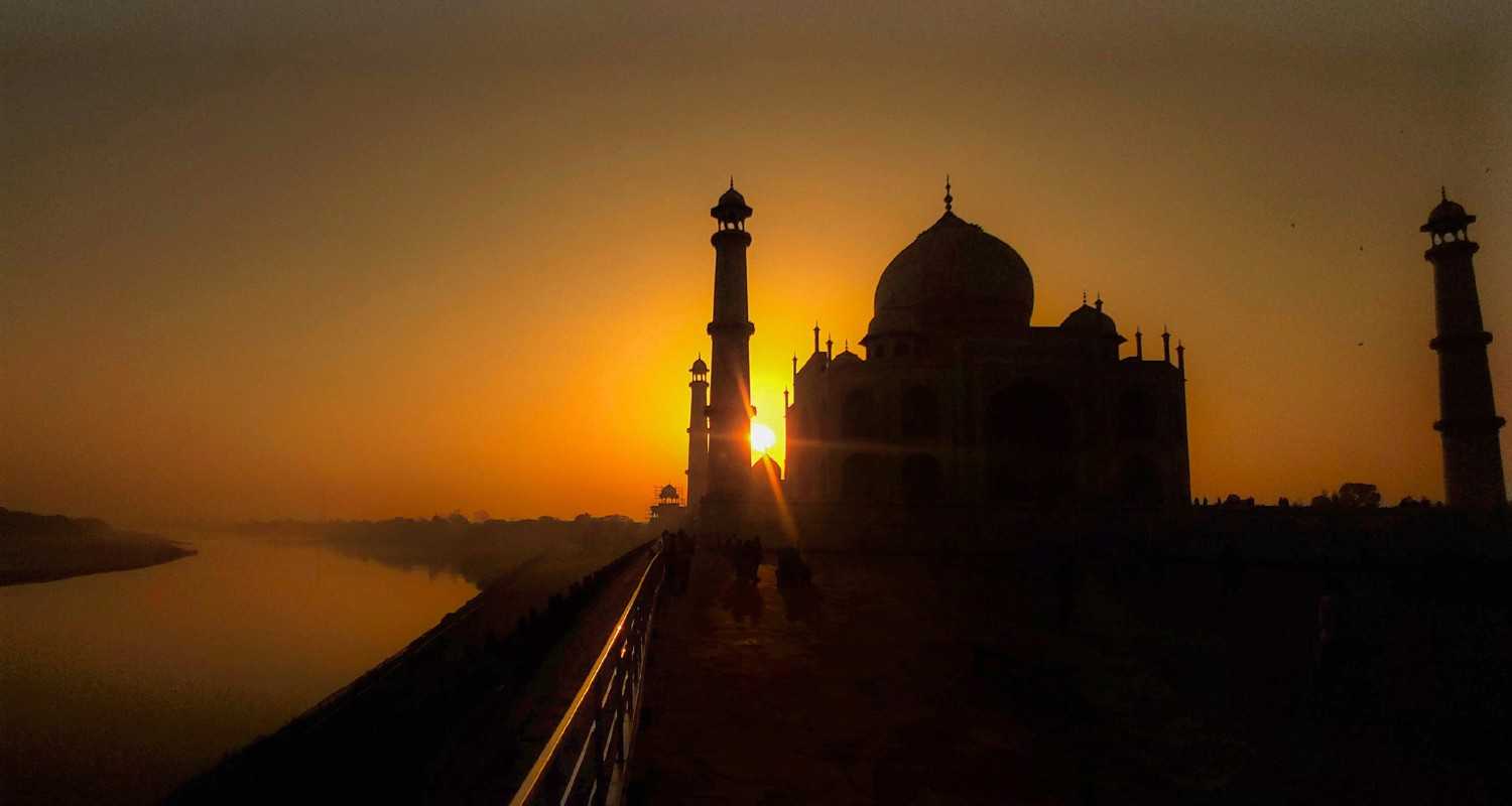 The silhouette of the Taj Mahal emerges against the vibrant hues of a sunrise, casting a mesmerising shadow that epitomizes the majestic beauty of India's architectural marvel.