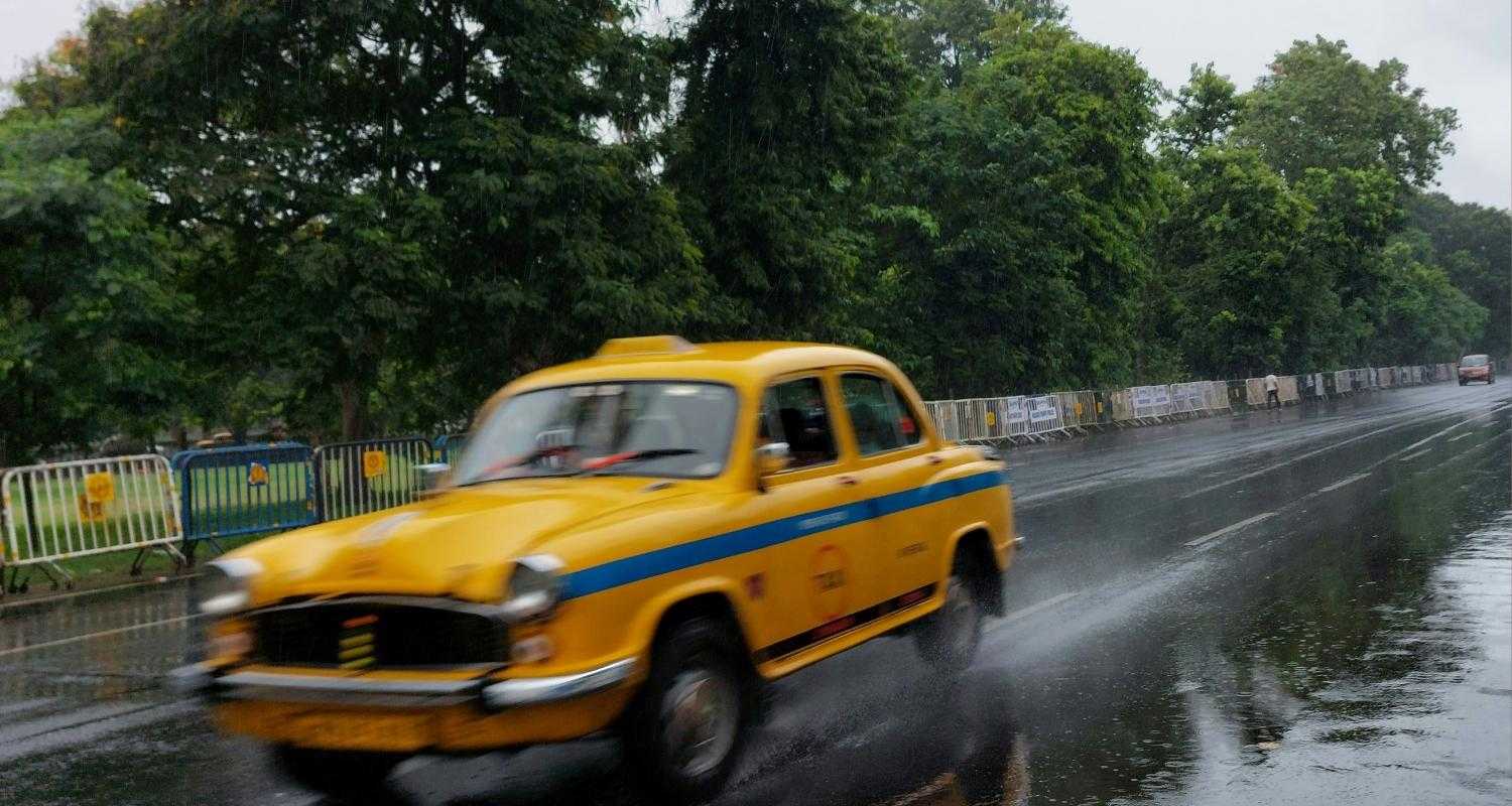 A yellow cab speeds by after rains in Kolkata. Via Unsplash.