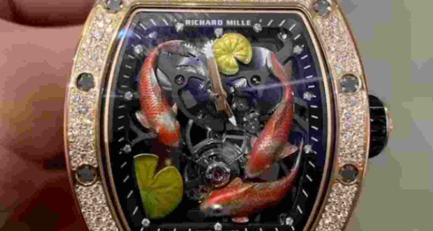 The image shows a luxurious Richard Mille wristwatch with a rose gold and diamond bezel. The dial features hand-painted orange and white koi fish among green lily pads on a black background, with visible mechanical gears and a tourbillon, highlighting a fusion of artistry and high-end watchmaking.