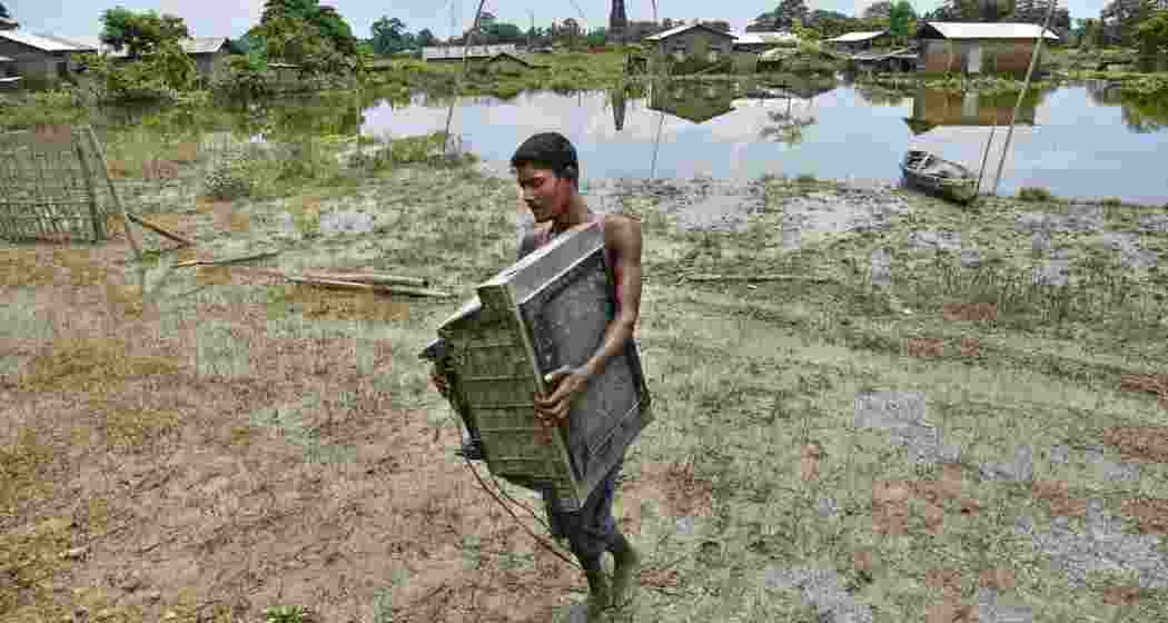 A villager moves his belongings to safety from a flood-affected area in Kaliabor, Nagaon district, Assam.