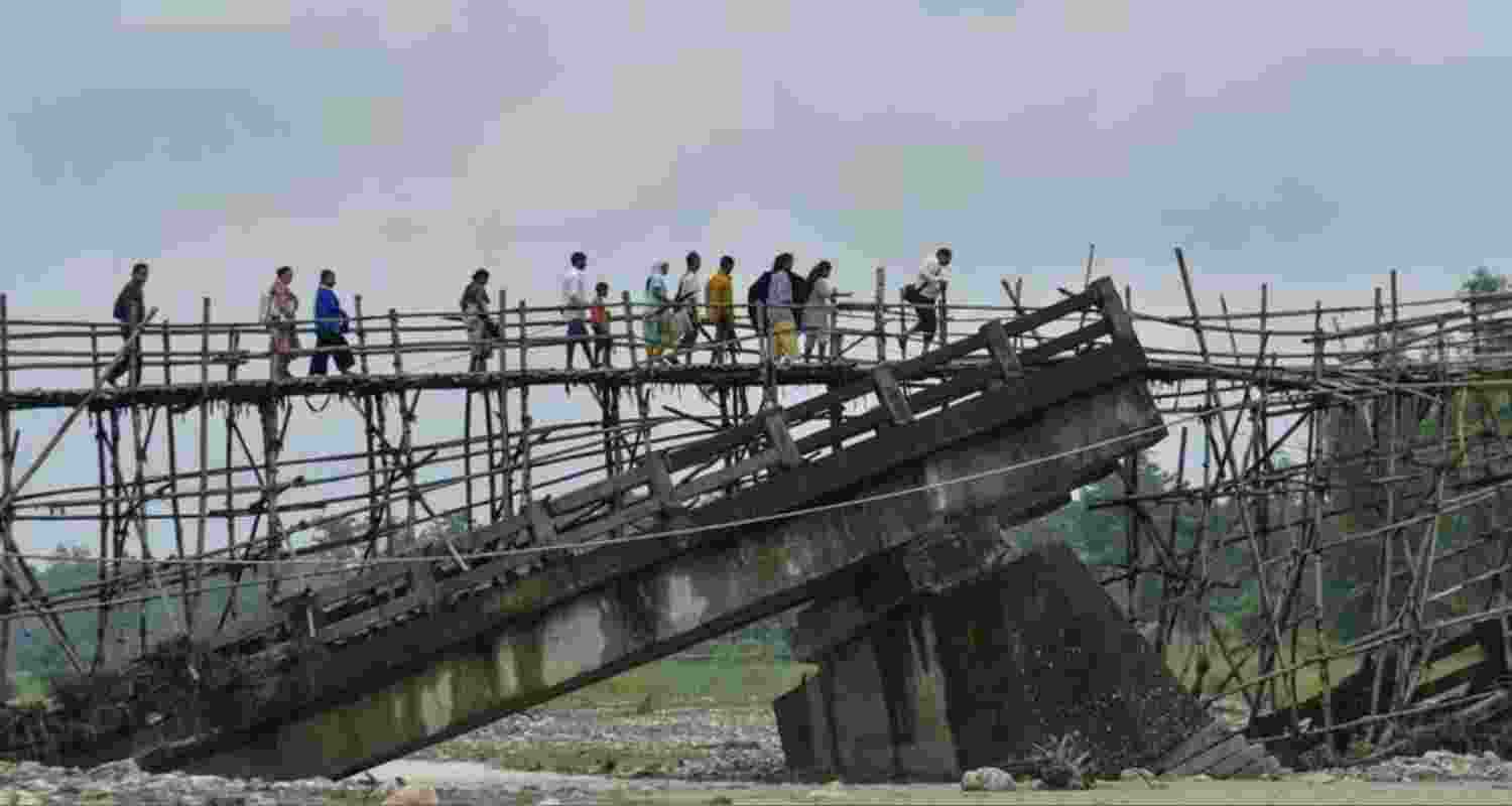 Villagers use a temporary bamboo bridge to cross a river after the RCC bridge over it washed away in flood water in Baksa district.