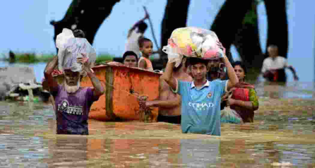 People wade through a flooded area in Bangladesh, navigating the rising waters caused by monsoon rains.