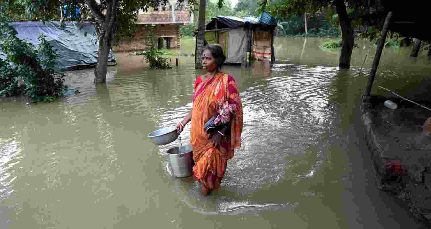 A village woman walks through a flooded area to collect drinking water following heavy rains, at Udaynarayanpur in Howrah district of West Bengal.