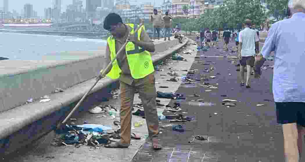 A BMC worker cleans up the waste left by fans at Marine Drive after India's T20 World Cup victory parade on Thursday night.