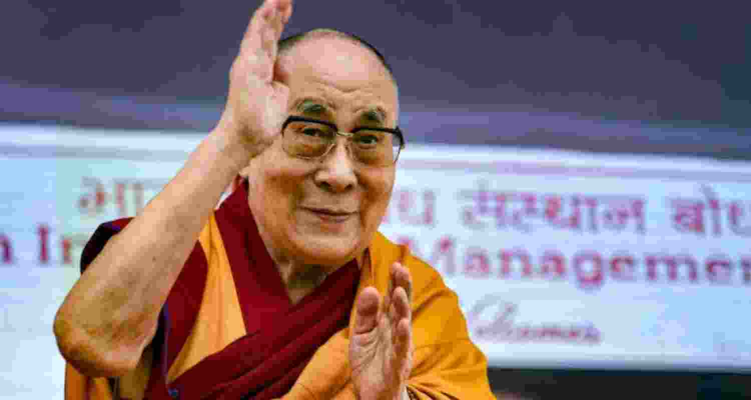 Tibetan Spiritual leader the Dalai Lama waving to spectators at an event.