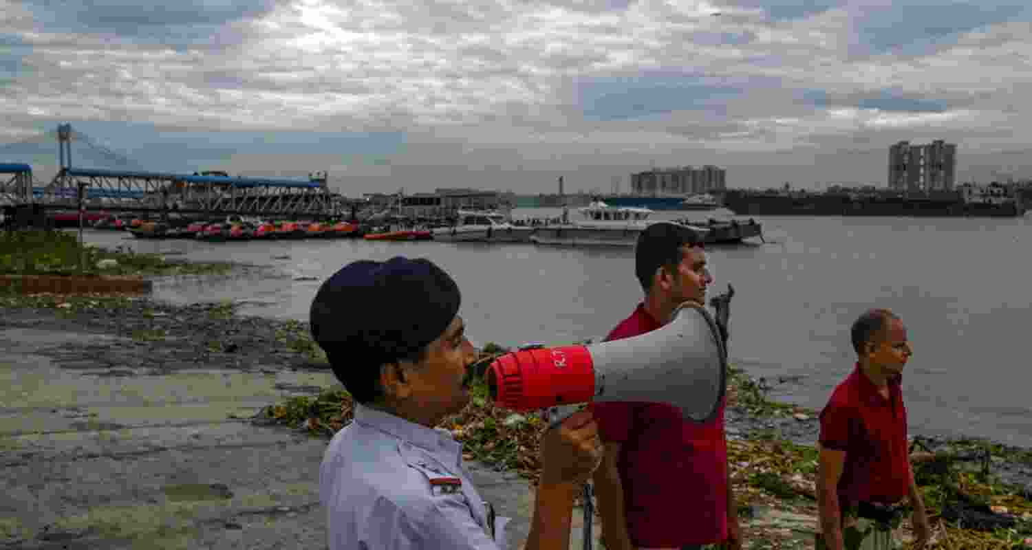 Officials of the River Traffic Police and Disaster Management Group (DMG) make announcements on the banks of the Hooghly river ahead of ahead of Cyclone 'Dana' landfall, in Kolkata, Wednesday. 