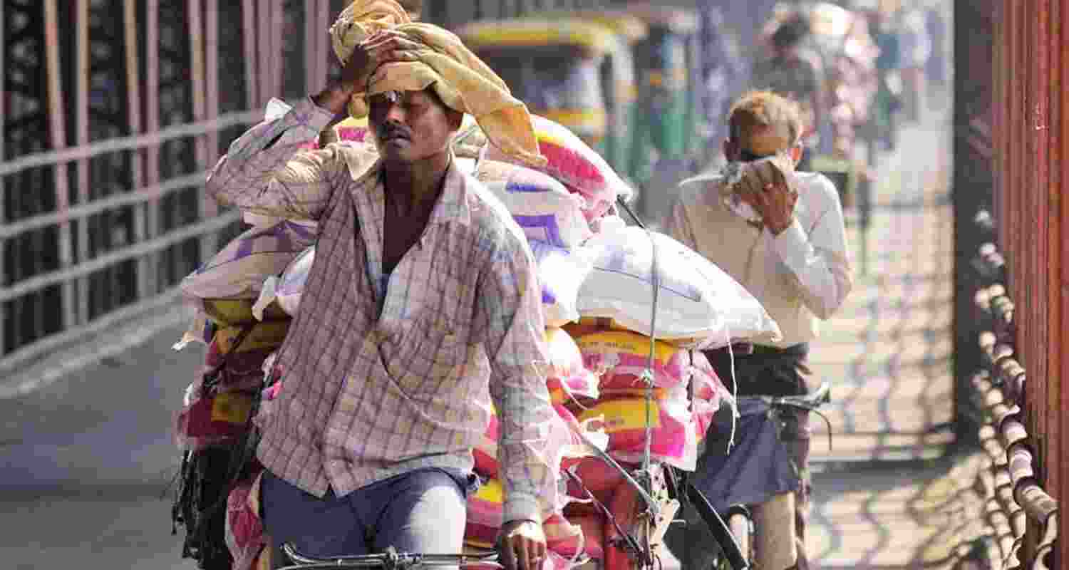 A man mops sweat from his brow while transporting goods on his cycle rickshaw across New Delhi's Old Yamuna bridge in sweltering weather.