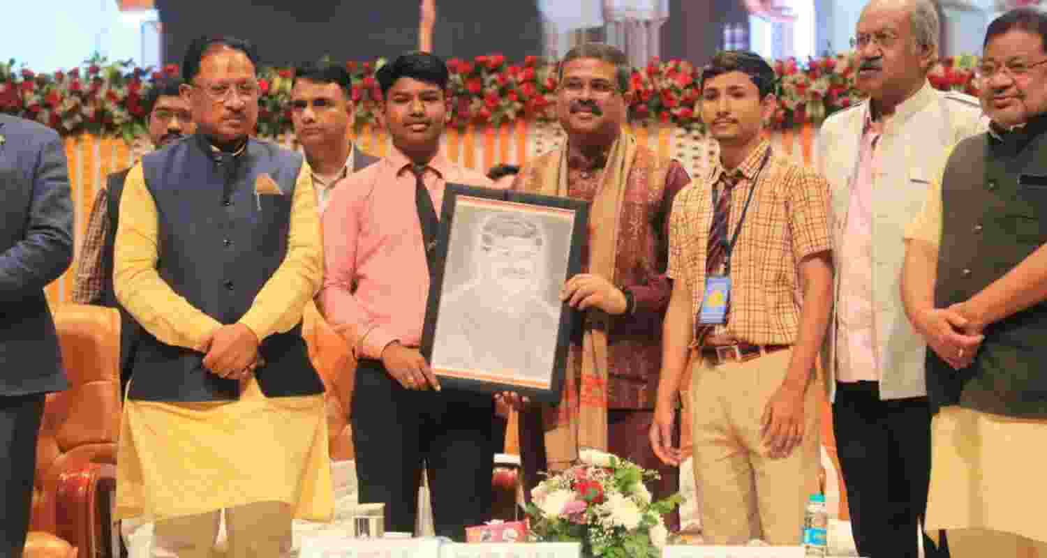 Union Minister Dharmendra Pradhan receives a gift from a student.