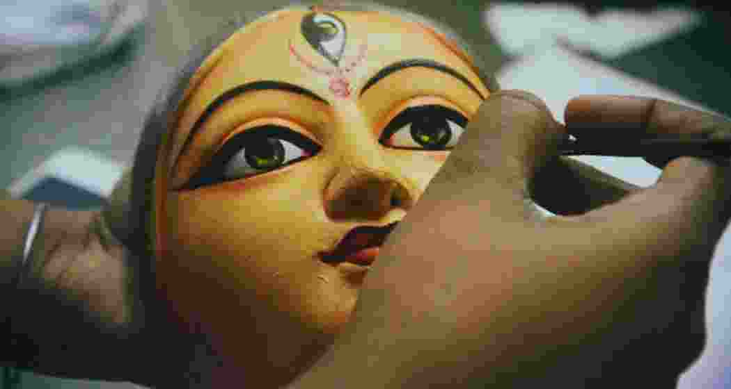 A sculptor carefully adds a stroke to the Durga idol in Kolkata's Kumortuli.