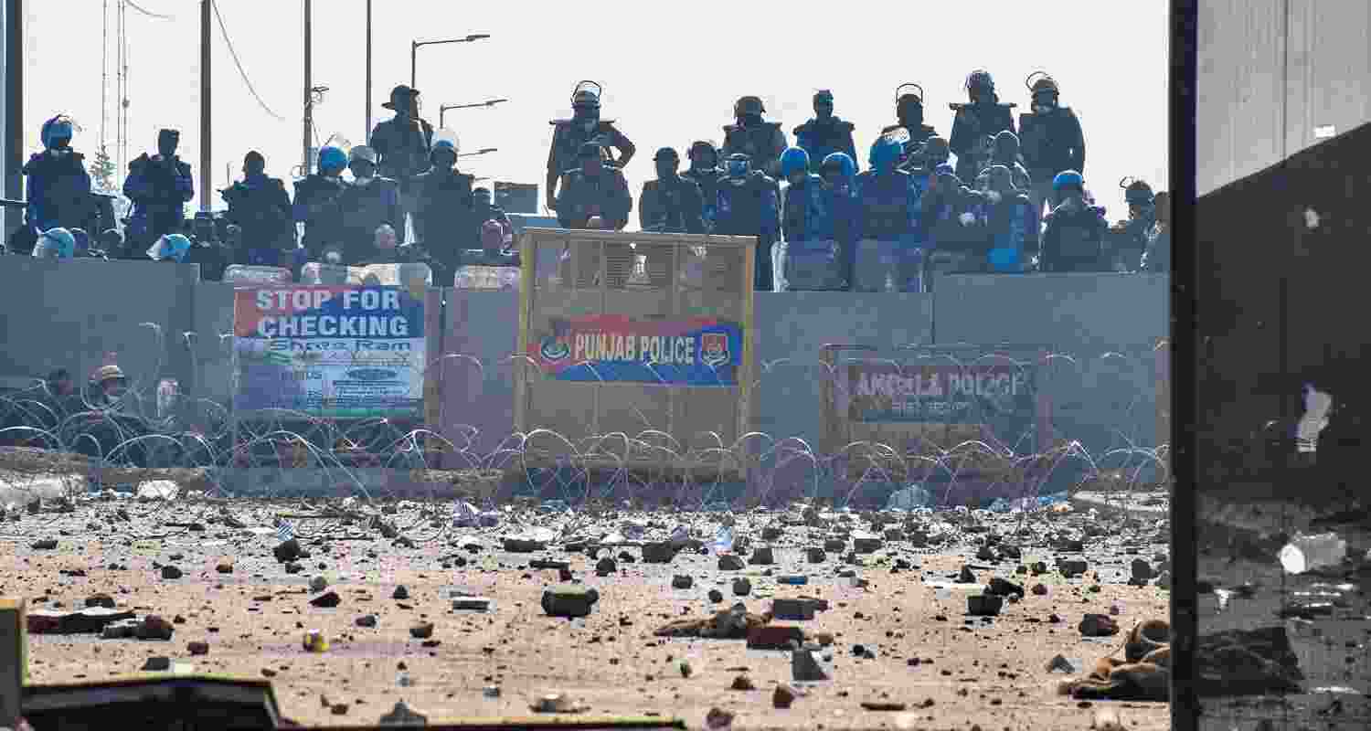 Security personnel stand guard as brick bats and stones lie on the roads at the Punjab-Haryana Shambhu border during farmers' 'Delhi Chalo' march, near Patiala district. 