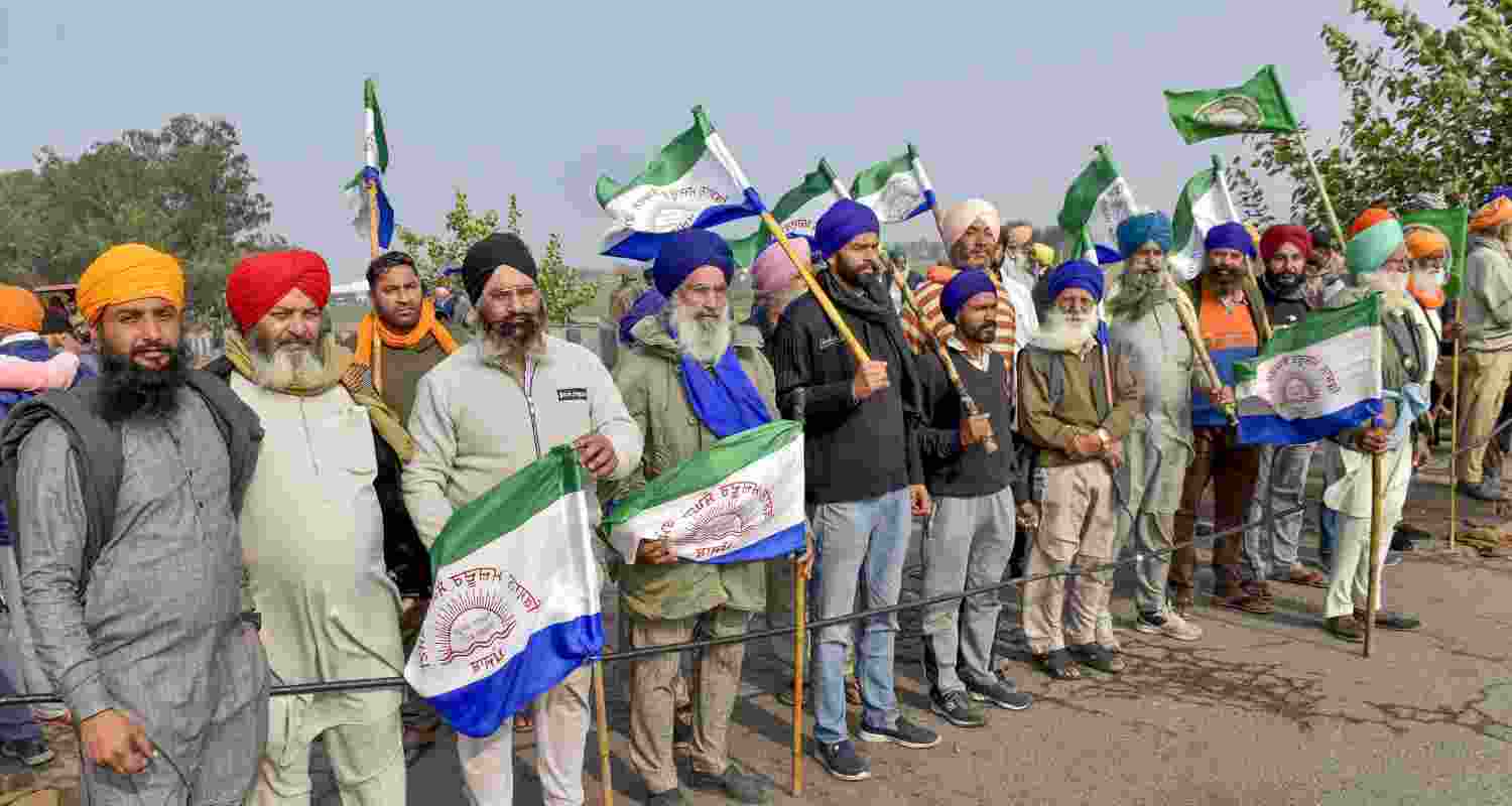 A group of farmers protesting at the Shambhu border with the BKU flags in their hands.