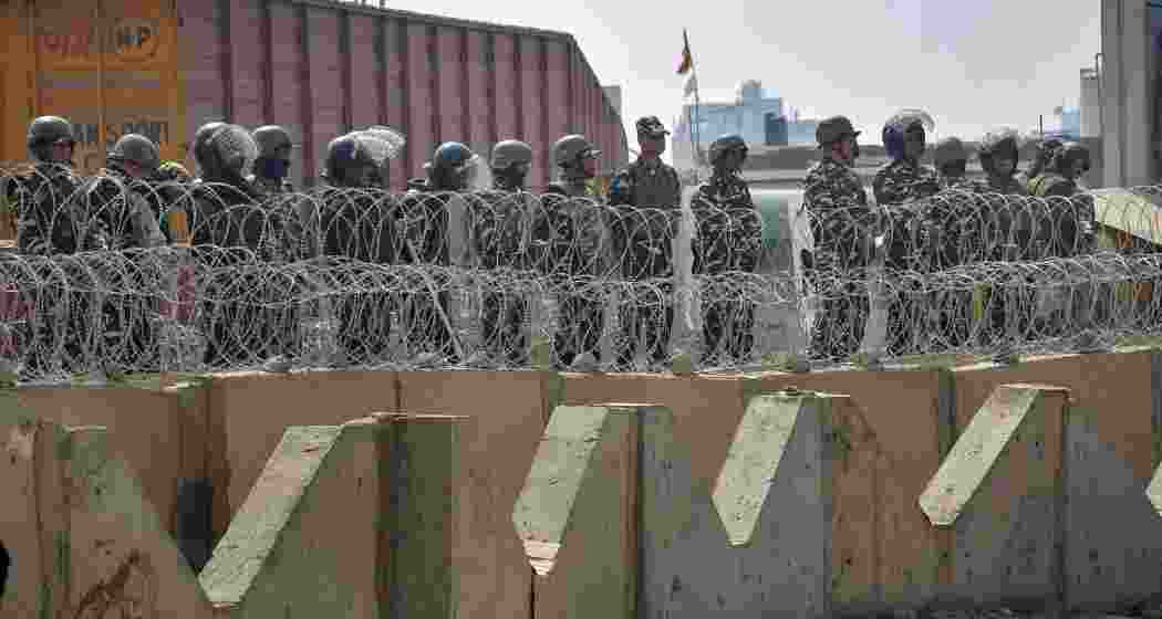 Security personnel stand guard during the protesting farmers Delhi Chalo March, at the Tikri Border, in New Delhi, Wednesday.