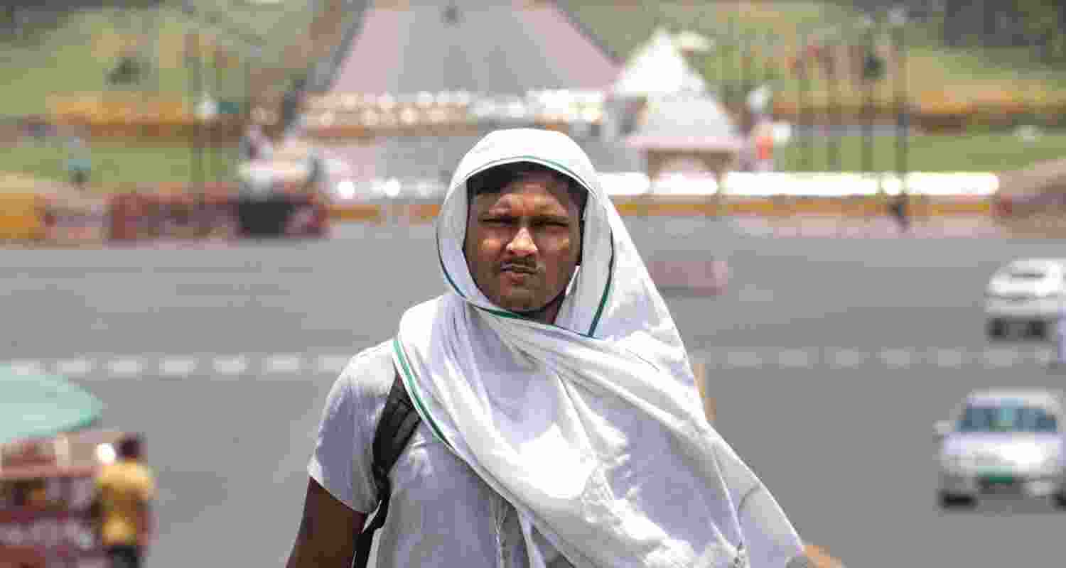 A man covers his head for protection from the scorching sun on a hot summer day, in New Delhi, Tuesday, June 18, 2024. The India Meteorological Department (IMD) has issued a 'red' alert because of prevailing heatwave conditions in the national capital.