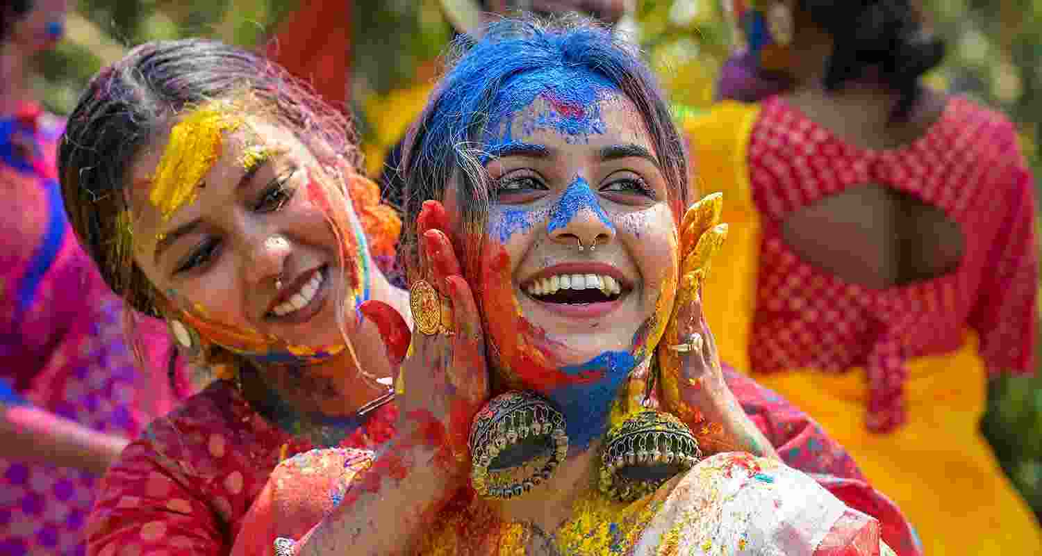 Women play with colours ahead of the festival of Holi, in Nadia
