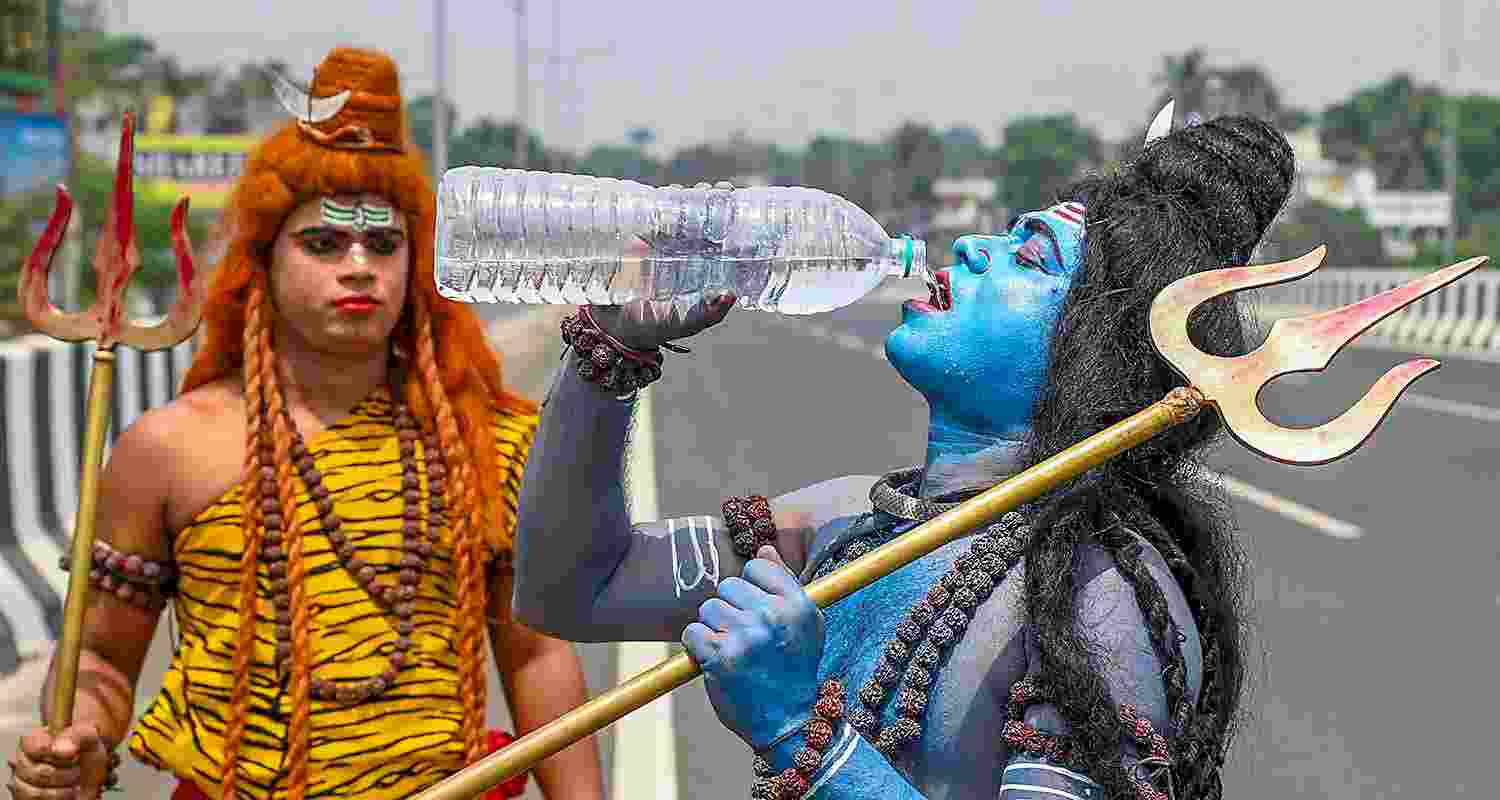 An artist dressed as Lord Shiva drinks water on a hot summer afternoon, in Nadia district