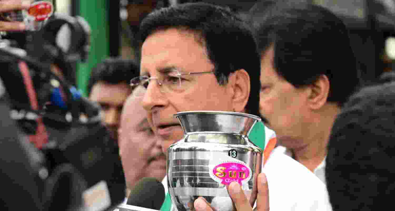 Surjewala in a press breifing comes up with an empty steel vessel showing BJP didn't give anything to Karnataka. Image X.
