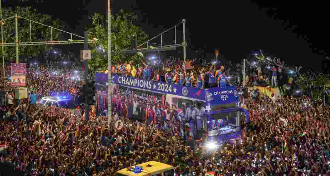 Players of the T20 World Cup-winning Indian cricket team with the championship trophy acknowledge fans during their open bus victory parade, in Mumbai, Thursday, July 4, 2024.