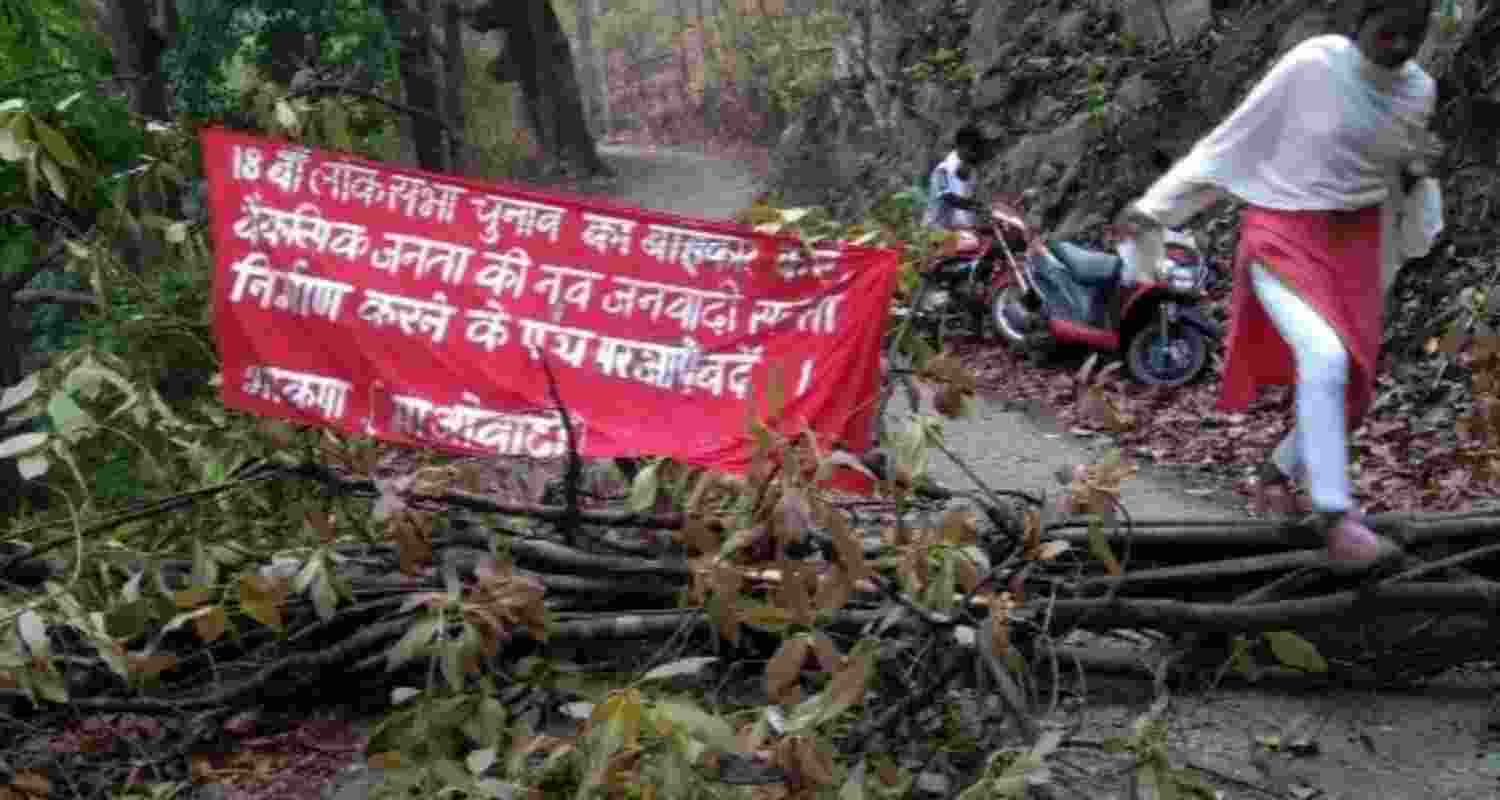 Maoists cut down trees and declare election boycott along rural road in Saranda forest.