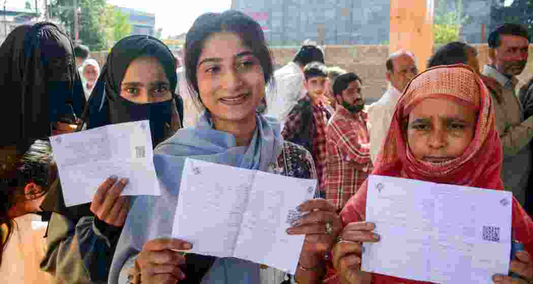 First time voters Rahila Younis (C), Humaira Jan (L) and others show their voting slips as they wait to cast votes at a polling station at Bijbehara during the first phase of Jammu and Kashmir Assembly elections, in Anantnag district, Wednesday, Sept. 18, 2024.