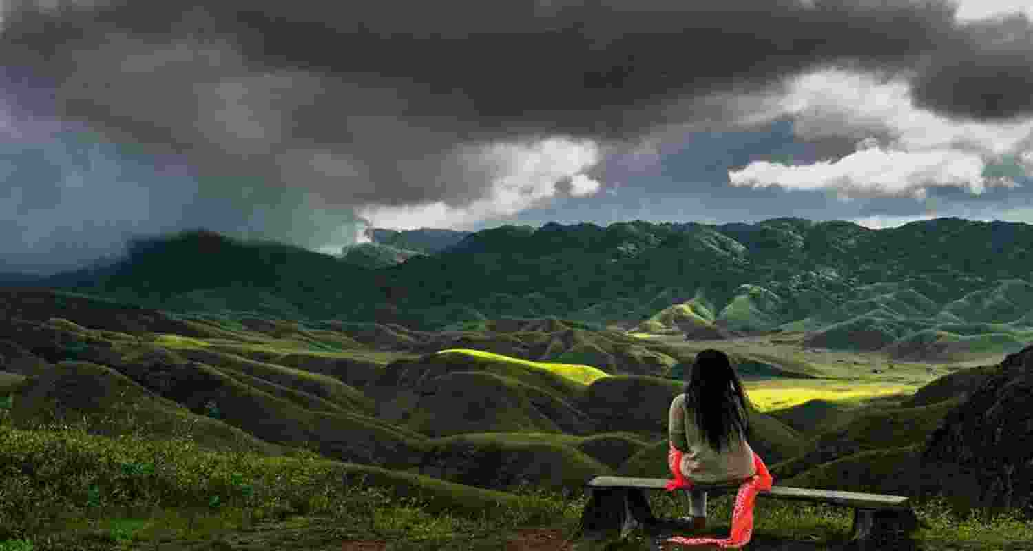 A woman gazes at the peacefully resting hilly areas of the Dzukou Valley on the Manipur-Nagaland border.