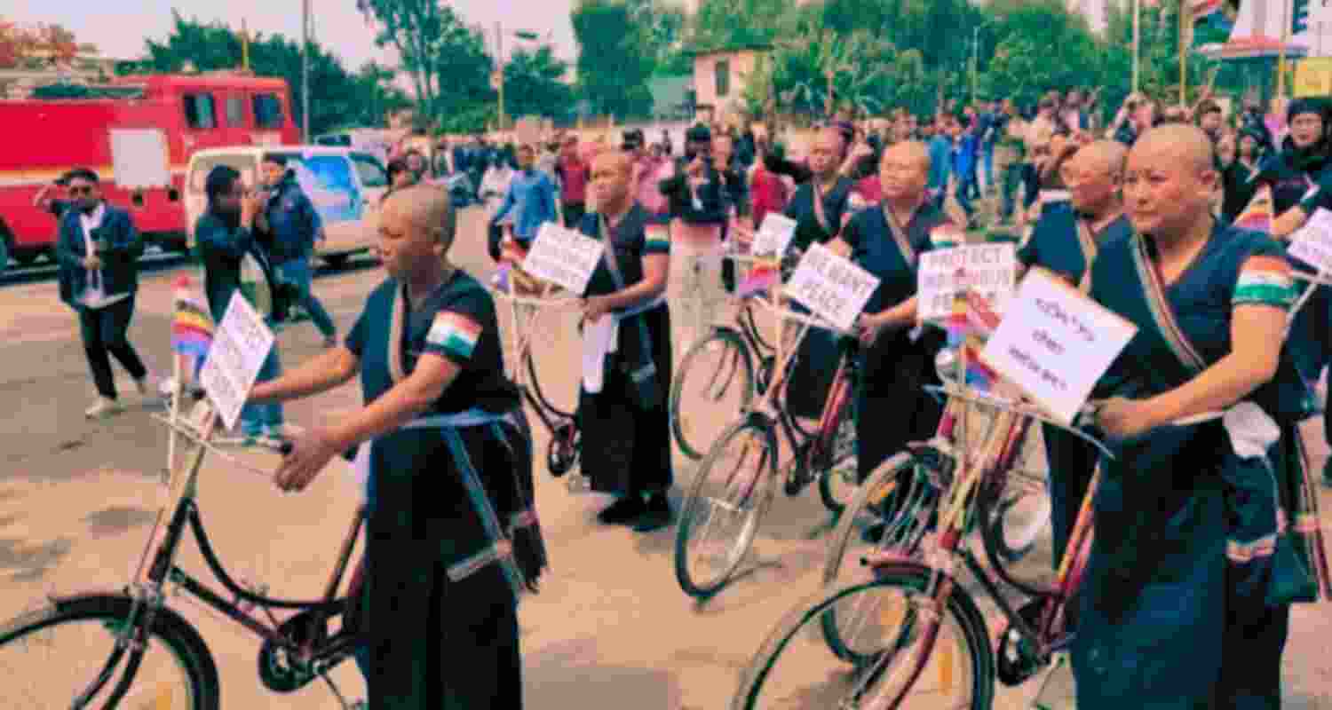 Women cyclists wielding placards expressing a desire for peace and rejecting demands for hill autonomy.