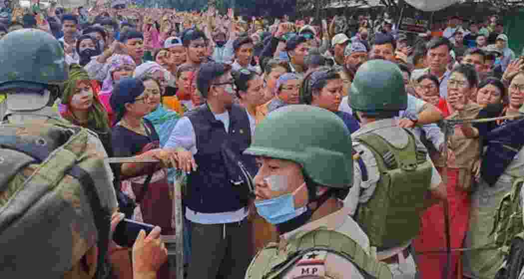 Protesters gather as security personnel block their way along a street during a curfew in Imphal on September 10, 2024.