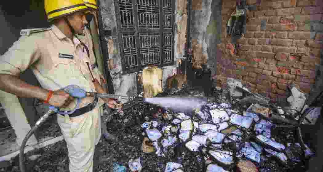 Police personnel douse a fire at a school that was torched after a four-year-old child was allegedly found dead near the school premises