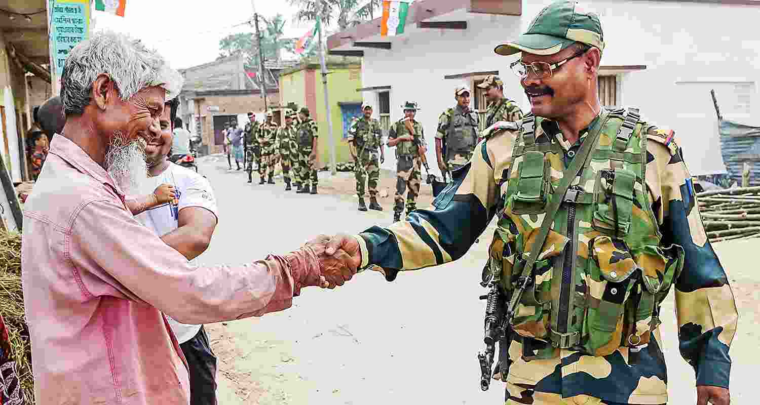 BSF personnel interact with locals during a route march ahead of Lok Sabha elections, in Nadia