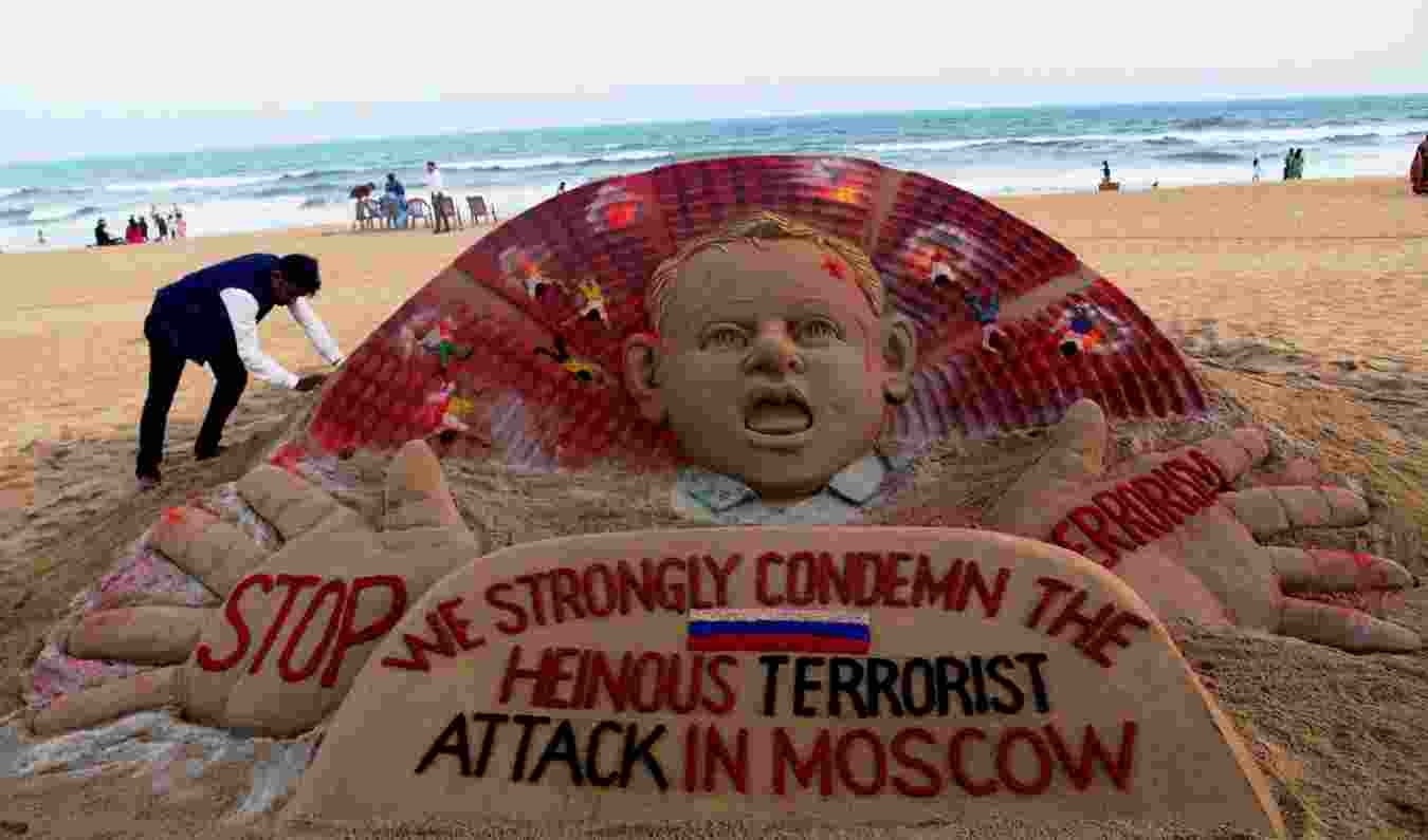 Artist Sudarsan Pattnaik at a beach in Odisha's Puri adding final touches to his sand sculpture condemning the Moscow concert hall attack. (PTI)