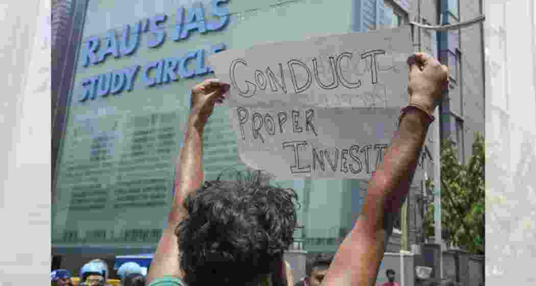 A student demonstrates in front of Rau's IAS Study Circle, demanding improved safety measures after recent tragic deaths.