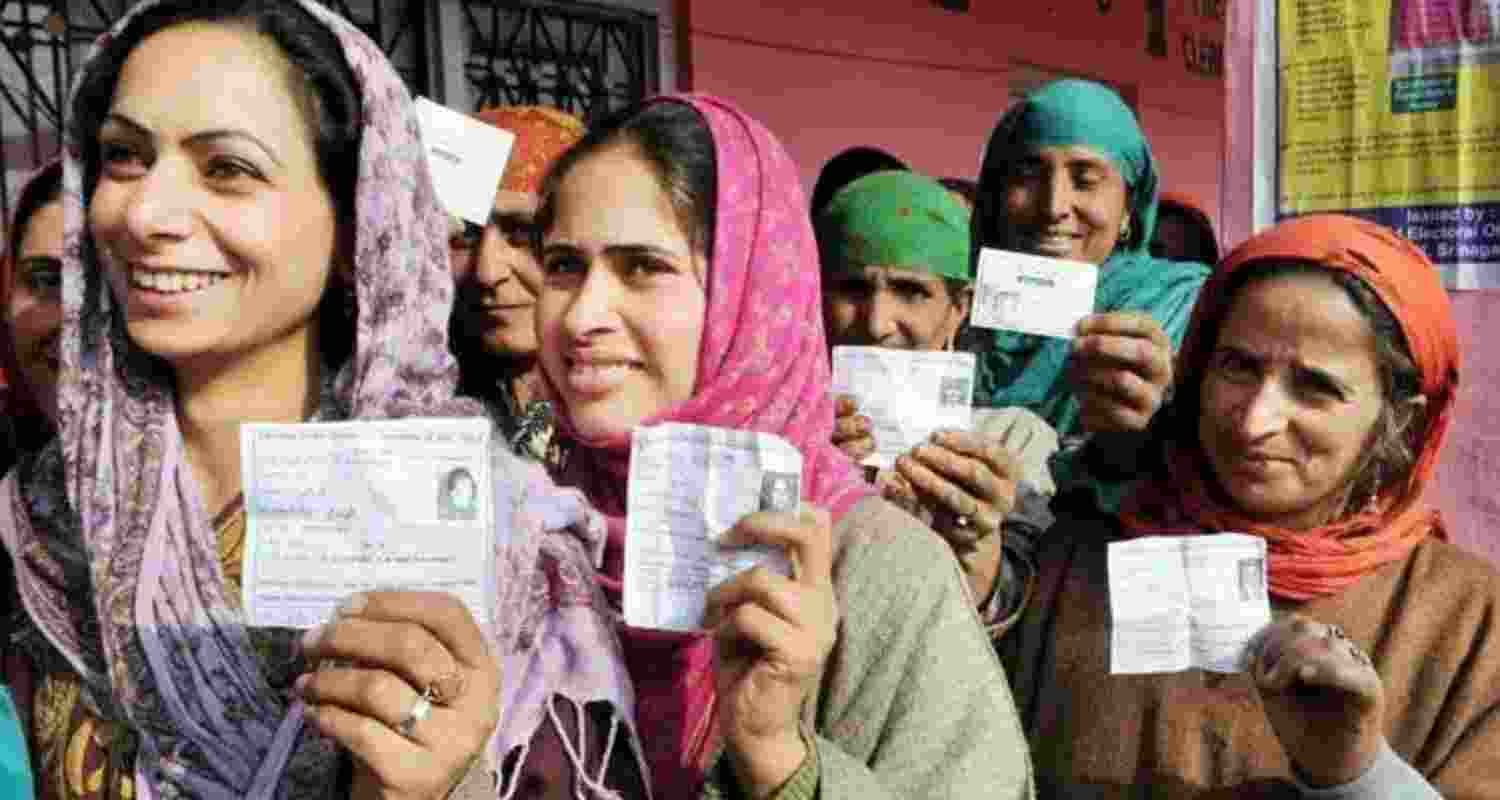 Women hold up their voter ID cards in Srinagar.