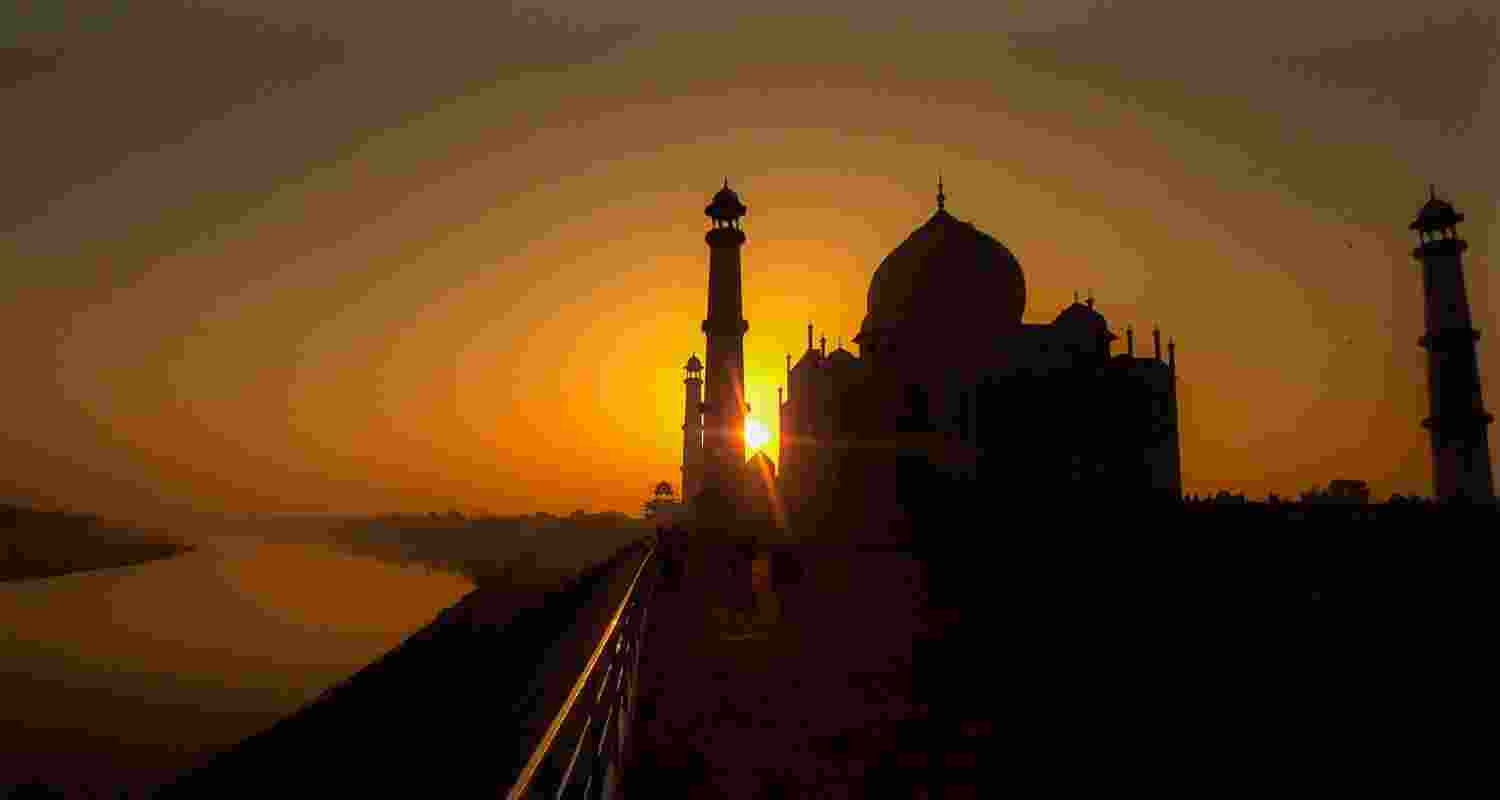 The silhouette of the Taj Mahal emerges against the vibrant hues of a sunrise, casting a mesmerising shadow that epitomizes the majestic beauty of India's architectural marvel.