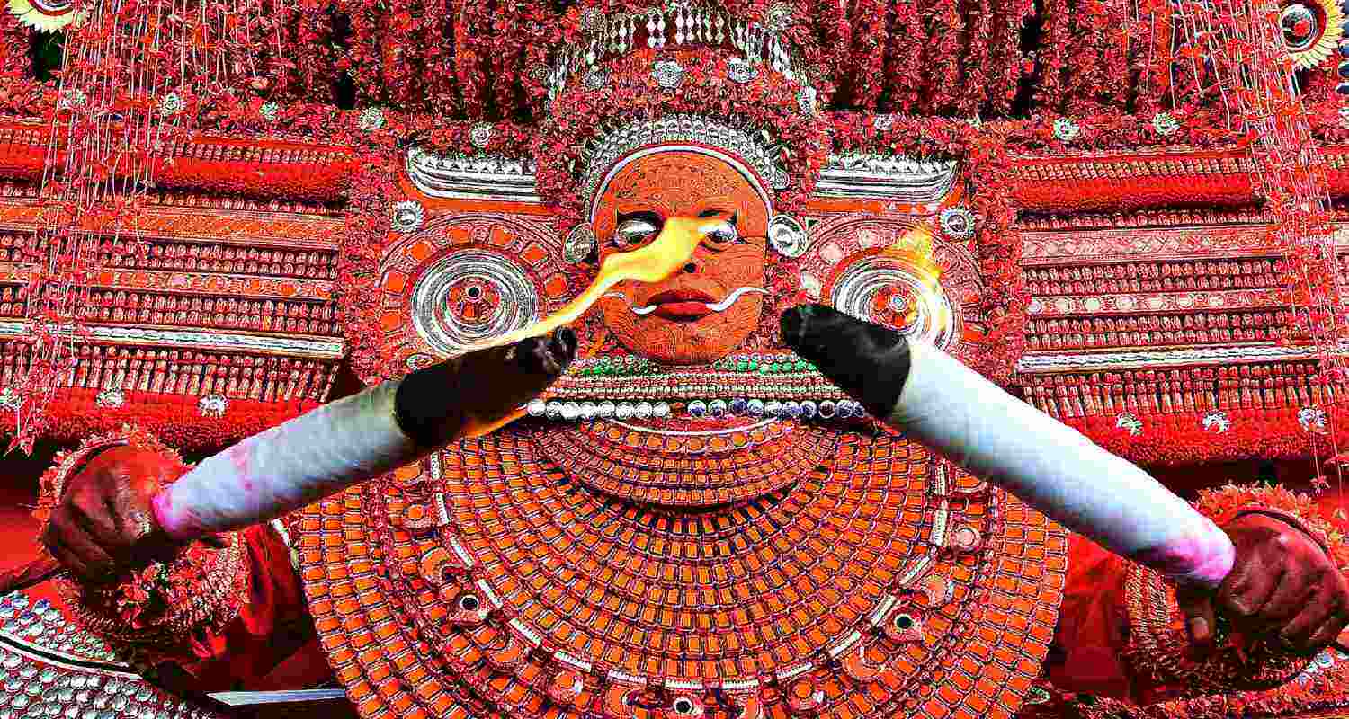 A Kerala Theyyam performer raises the thirumudi, the royal crown of the Muchilot Bhagavathi goddess during the festival in Kannur, Kerala