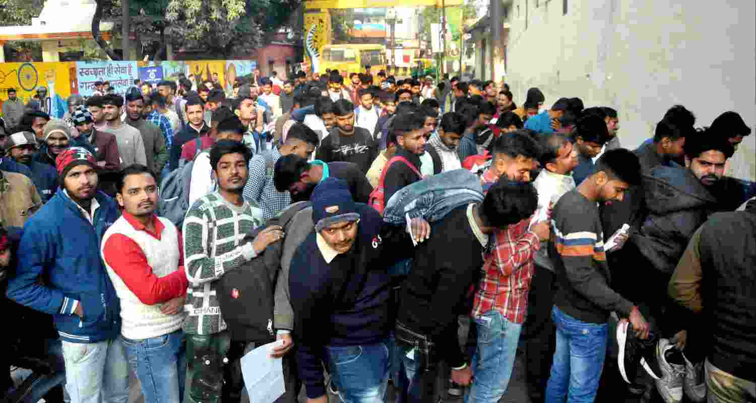 Candidates wait outside an examination centre to appear in the UP Police Constable recruitment exam. 