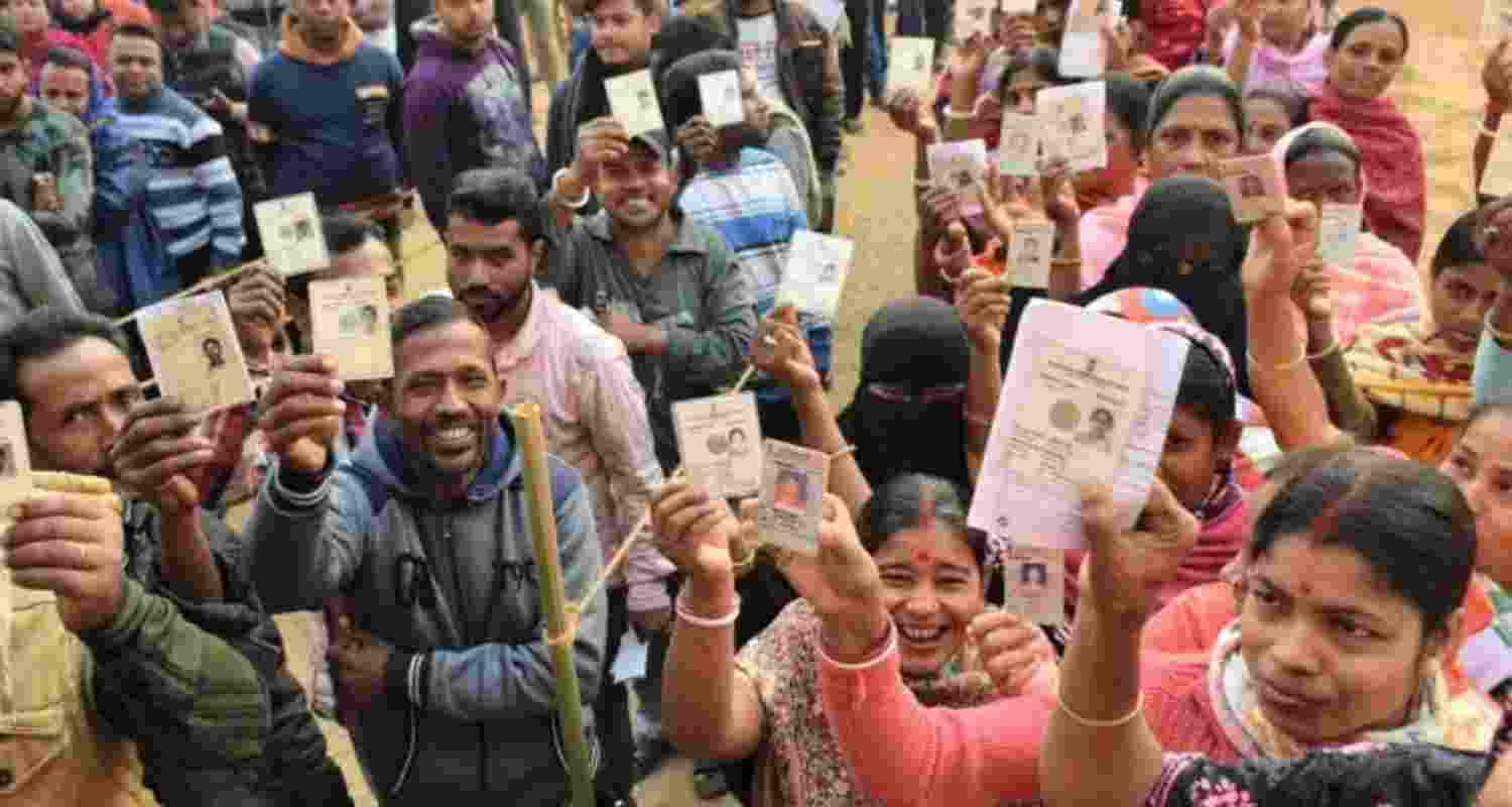 Electorates show voter ID cards while standing queue to vote.