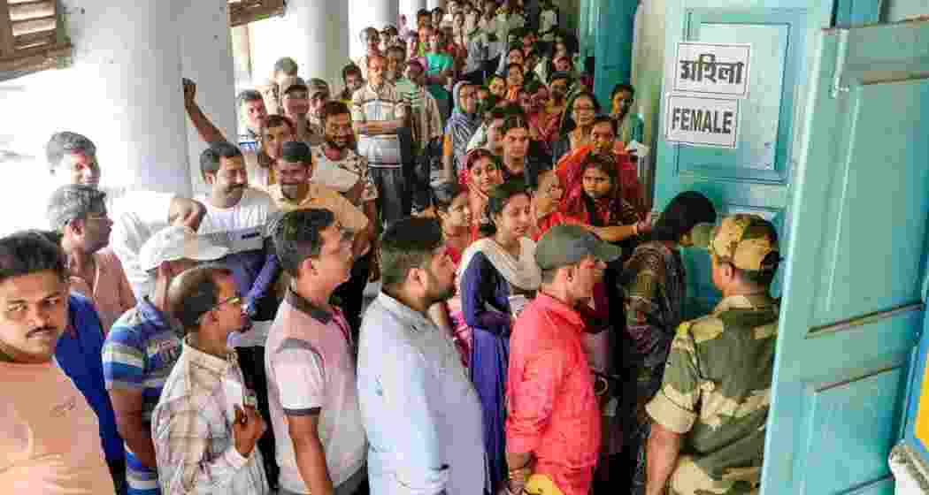 Voters wait in a queue at a polling station to cast their votes for the fourth phase of Lok Sabha elections, in Bardhaman on Monday, May 13, 2024.