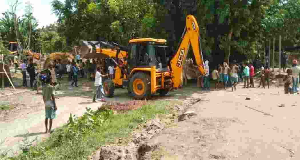A backhoe loader demolishes structures as protesters clash with security forces during an eviction drive in Assam’s Darrang district, leaving two dead and several injured back in 23 September 2021.