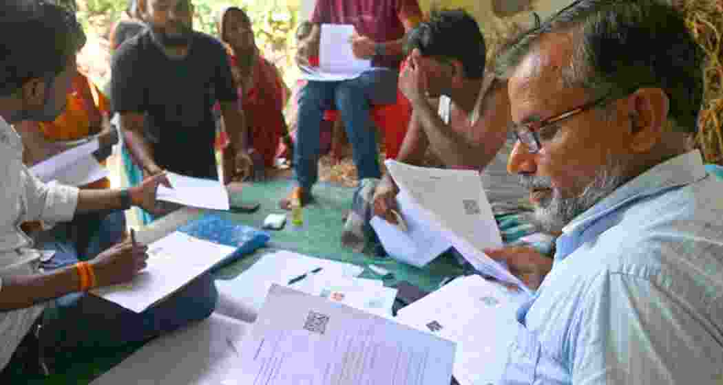 A BLO verifies voter documents during the Special Intensive Revision drive.