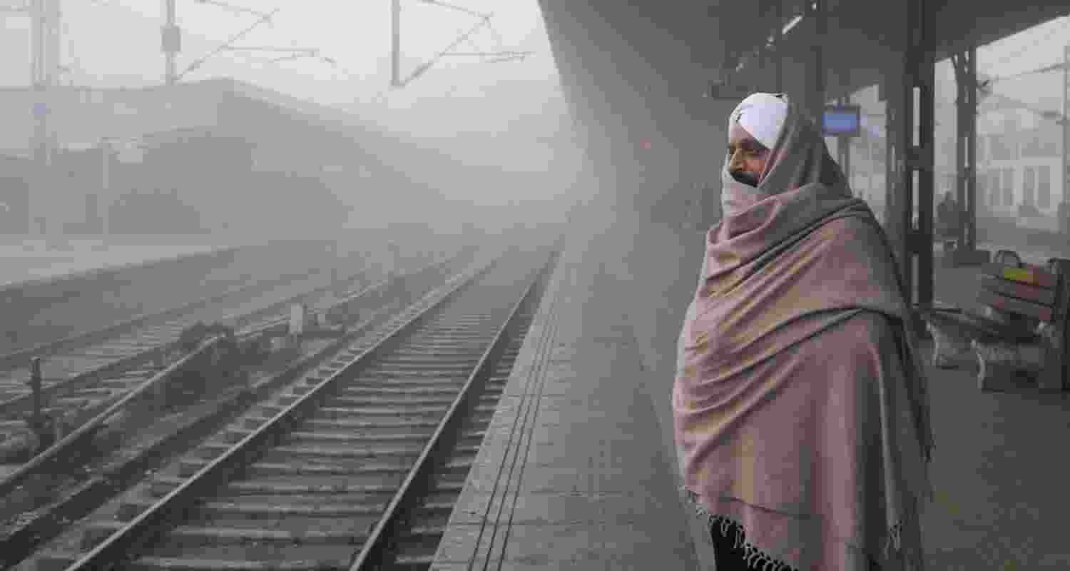 A commuter waits for a train at a railway station amid dense fog during a cold winter morning, in Amritsar. 