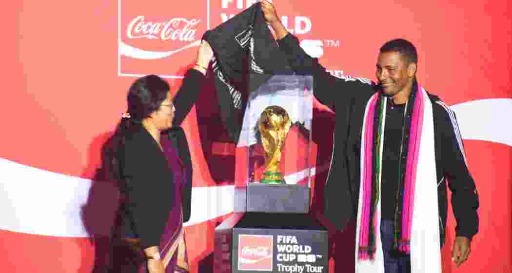 Assam Sports Minister Nandita Gorlosa and Brazil World Cup winner Gilberto Silva unveil the FIFA World Cup Trophy at Barsapara Stadium, Guwahati, with fans and officials witnessing the event.